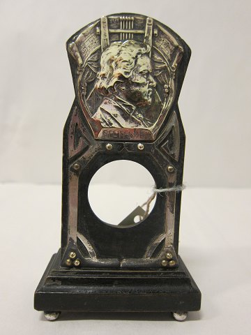 Uhrenhalter
Ein alter/antiker Uhrenhalter aus Holz gemacht mit einer Besatz von Messing, 
woran "Beethoven" ist angeschrieben
Um 1890-1920
Der Uhrenhalter ist ursprünglich für eine Dametaschenuhr gemacht
H: 14,5cm, B: 8cm