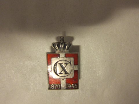 Kongemærket (Königabzeichen) aus Sterling Silber 925S mit rotem Email-Motiv von 
Dannebrog
Diese Model ist für das Knopfloch
Jahr 1870-1945 und Christian X.
Die Georg Jensen Silberschmiede hat sie produciert