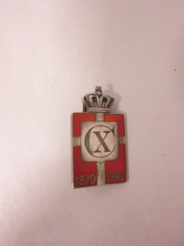 Kongemærket (Königabzeichen) aus Sterling Silber 925S mit rotem Email-Motiv von 
Dannebrog
Diese Model ist eine Brosche
Jahr 1870-1940 und Christian X.
Die Georg Jensen Silberschmiede hat sie produciert