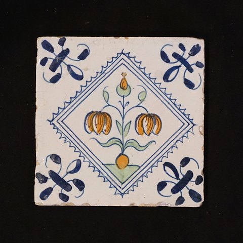 A 17th century polychrome decorated Dutch tile 
with flowers. Circa 1620-40. Size: 13x13cm